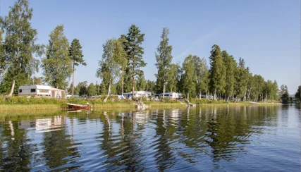 Utsikt från sjön till campingen, där husvagnar står direkt vid vattnet.